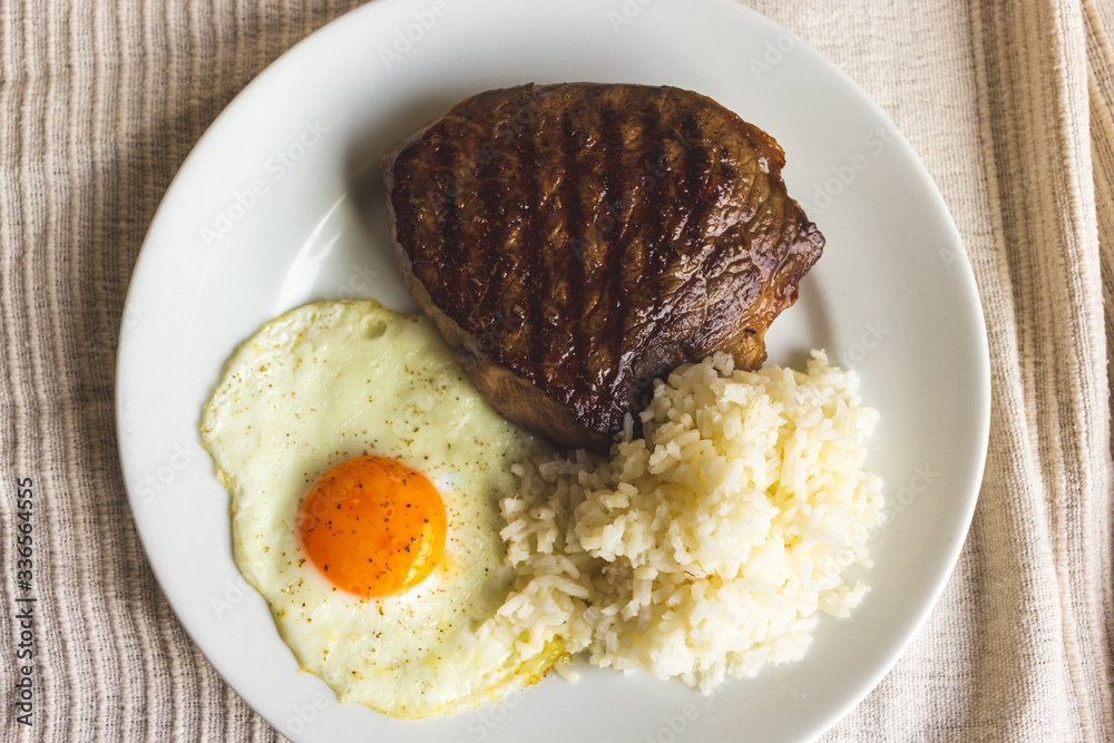 fried egg, steak and rice on white plate