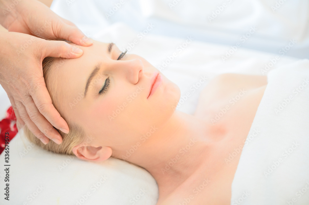 Beautiful woman receiving head and facial massage in spa salon. Concept of body health care and traditional thai massage relax