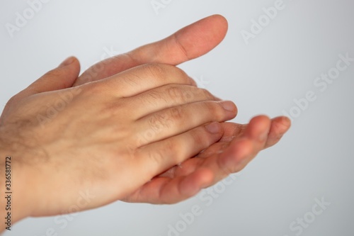 Closeup of rubbing hands with sanitizer on a white background, to prevent spread of coronavirus photo