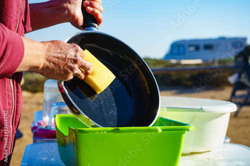 Woman washing dishes in bowl, capming outdoor photo