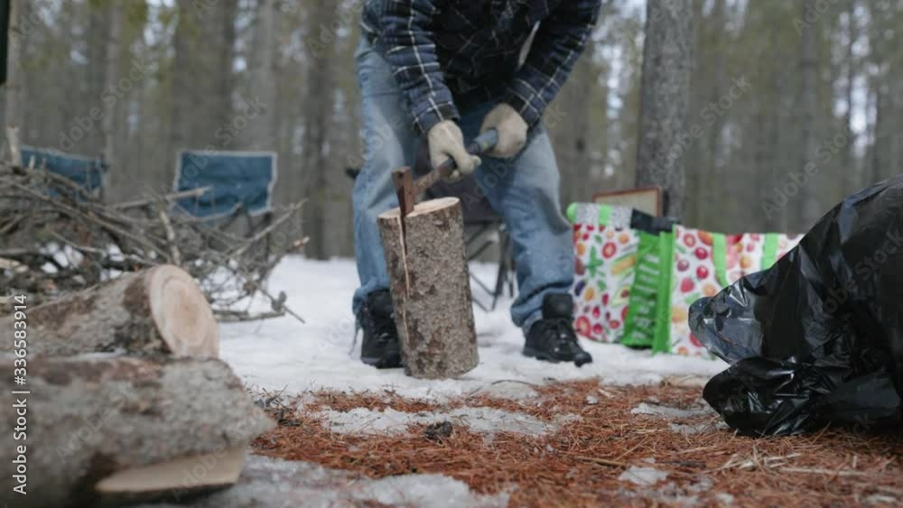 Man slamming a log with an axe stuck in it into the snowy ground. Canada Alberta. Wide Angle lens deep depth of field. Slow motion 120fps Man slamming a log with an axe stuck in it into the snowy ground. Canada Alberta. Wide Angle lens deep depth of field. Slow motion 120fps