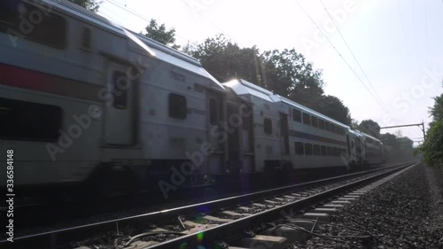 SLOW MOTION: End of commuter train, close up, as it passes by on the train tracks and leaves frame photo