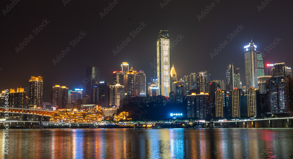 Night neon ight pano view of historic traditional architecture in Hongya Dong cave by Jialing river in Chongqing, China