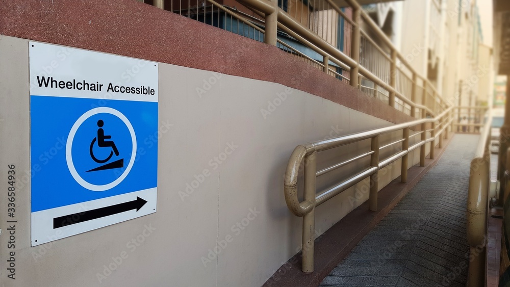 Blue Wheelchair accessible Sign and concret ramp way with handrail for ...