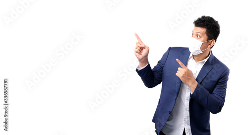 Business Asian man wearing a mask Pointing finger isolated on white background in studio With copy space, to prevent infection covid-19 health treatment.Health concept.