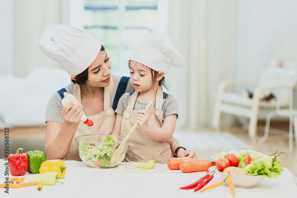Happy family mom teaching cute girl preparing and cooking healthy salad for the first time. first lesson and healthy lifestyle concept. Happy family mom teaching cute girl preparing and cooking healthy salad for the first time. first lesson and healthy lifestyle concept.