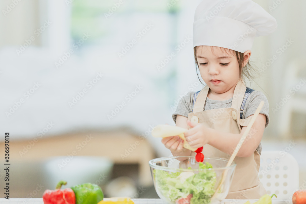 Sweet little cute girl is learning how to make a salad, in the home kitchen, Family concept, Vintage color tone. Sweet little cute girl is learning how to make a salad, in the home kitchen, Family concept, Vintage color tone.