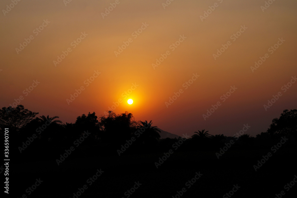 Sunset in the rural village of India, beside the mountains through the vegetation at evening time