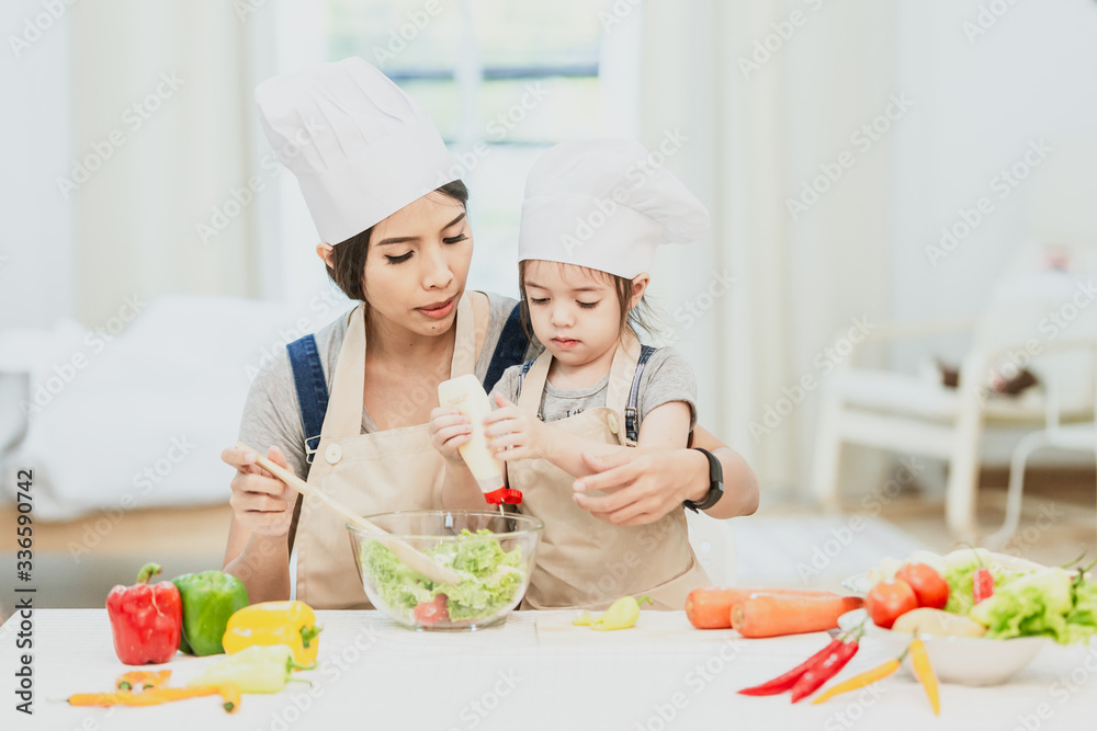 Happy family mom teaching cute girl preparing and cooking healthy salad for the first time. first lesson and healthy lifestyle concept.
