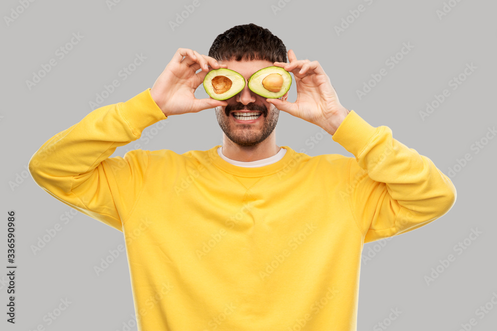 food, eating and people concept - smiling young man in yellow sweatshirt with avocado instead of eyes over grey background food, eating and people concept - smiling young man in yellow sweatshirt with avocado instead of eyes over grey background
