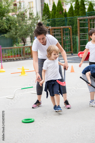 Beautiful little boy playing hockey within polygon. Sport school. Coach helping