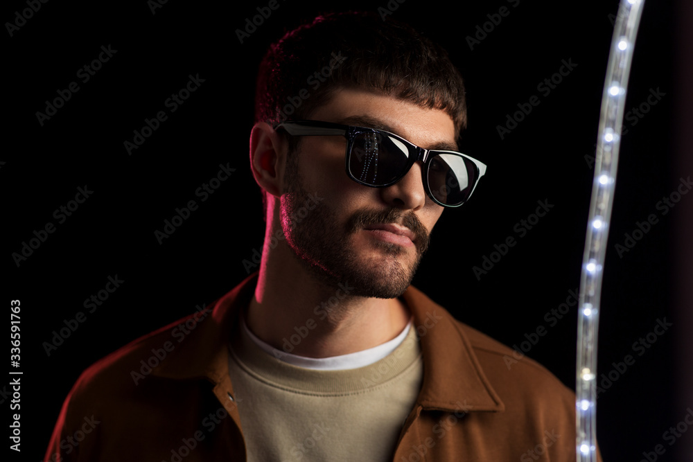 leisure, clubbing and nightlife concept - young man in sunglasses ain dark room over ultra violet neon lights at night club leisure, clubbing and nightlife concept - young man in sunglasses ain dark room over ultra violet neon lights at night club