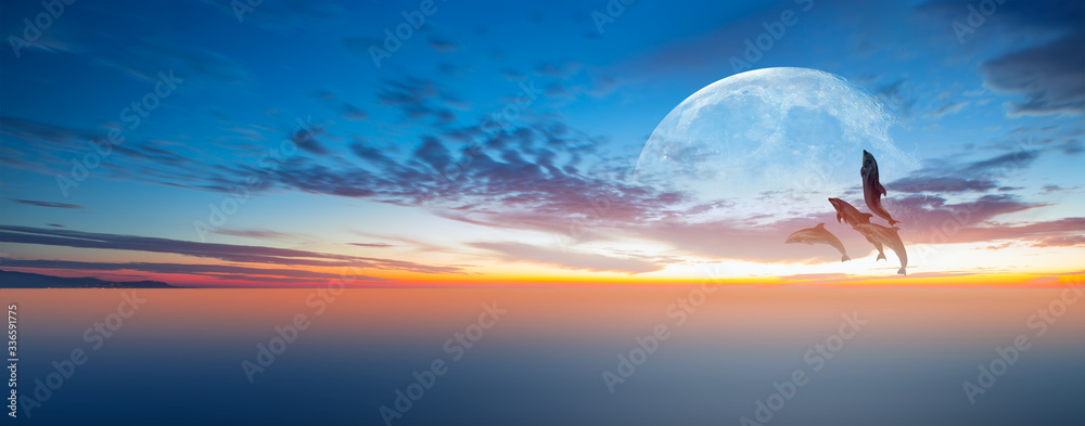 Fototapeta premium Silhoutte of dolphins jumping up from the sea at sunset with full moon 