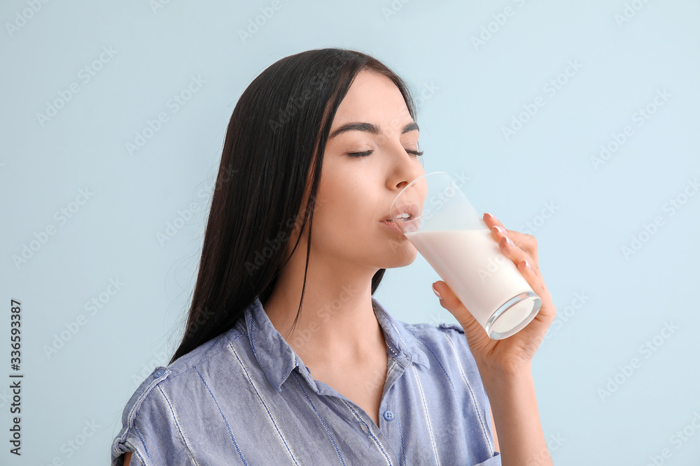 Beautiful young woman drinking milk on color background Beautiful young woman drinking milk on color background