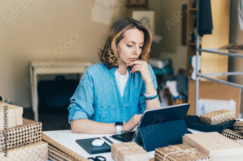 Young charming caucasian woman is working on a tablet. The designer models the order on a computer gadget. Home office and remote work concept. photo