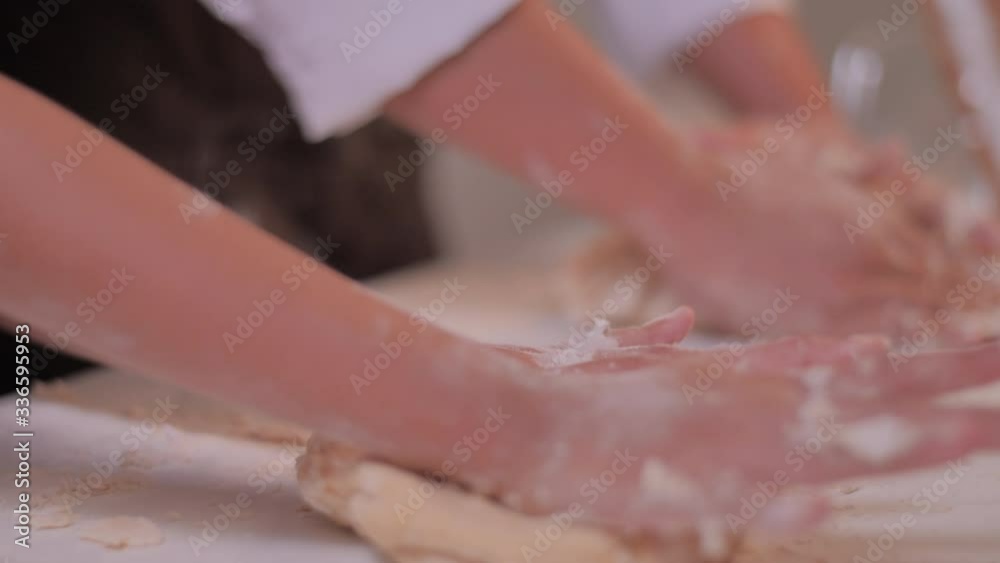 Close-up the hands are kneading the dough for making the bakery on the white table. Close-up the hands are kneading the dough for making the bakery on the white table.