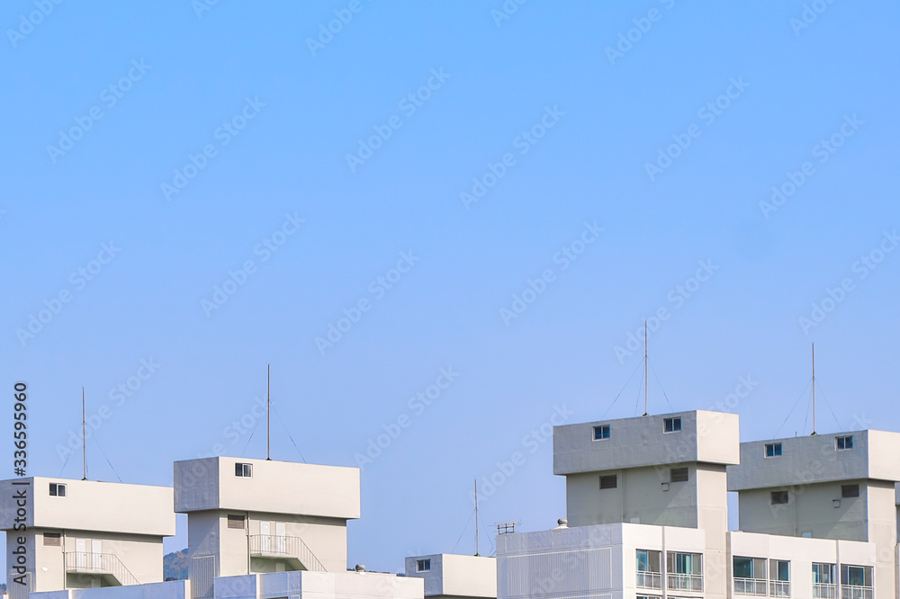 Tops of contemporary urban buildings against a clear blue sky.