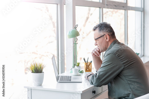 Mature man using laptop at ...