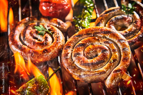 Canvas Print Close up on spicy coils of sausage grilling on BBQ