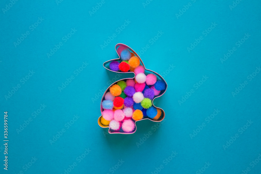 Rabbit bunny shaped form for gingerbread decorated with colorful balls inside on blue turquoise background with copy space. Easter concept