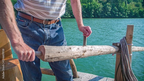 Close-up of strong raftsman on the Drava river using an oar to steer a log-raft photo