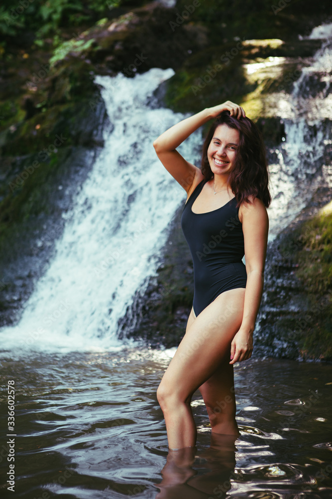 gorgeous woman in sexy black swimsuit in front of waterfall gorgeous woman in sexy black swimsuit in front of waterfall