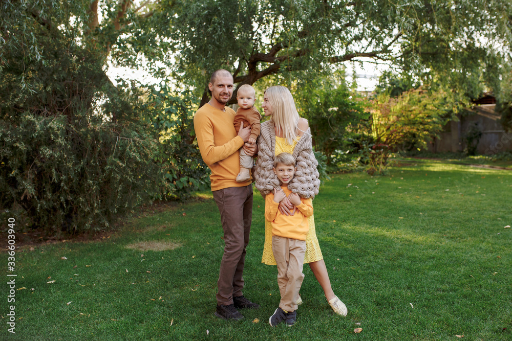 Obraz premium family in nature, summer or autumn, green grass trees in green leaves, a pond in nature, mom blonde in a yellow dress, dad, husband, older son and youngest son, two children, a large and happy family