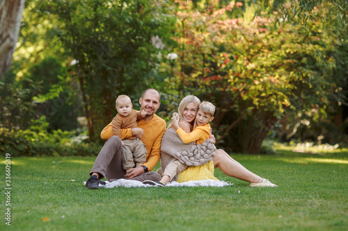  family in nature, summer or autumn, green grass trees in green leaves, a pond in nature, mom blonde in a yellow dress, dad, husband, older son and youngest son, two children, a large and happy family