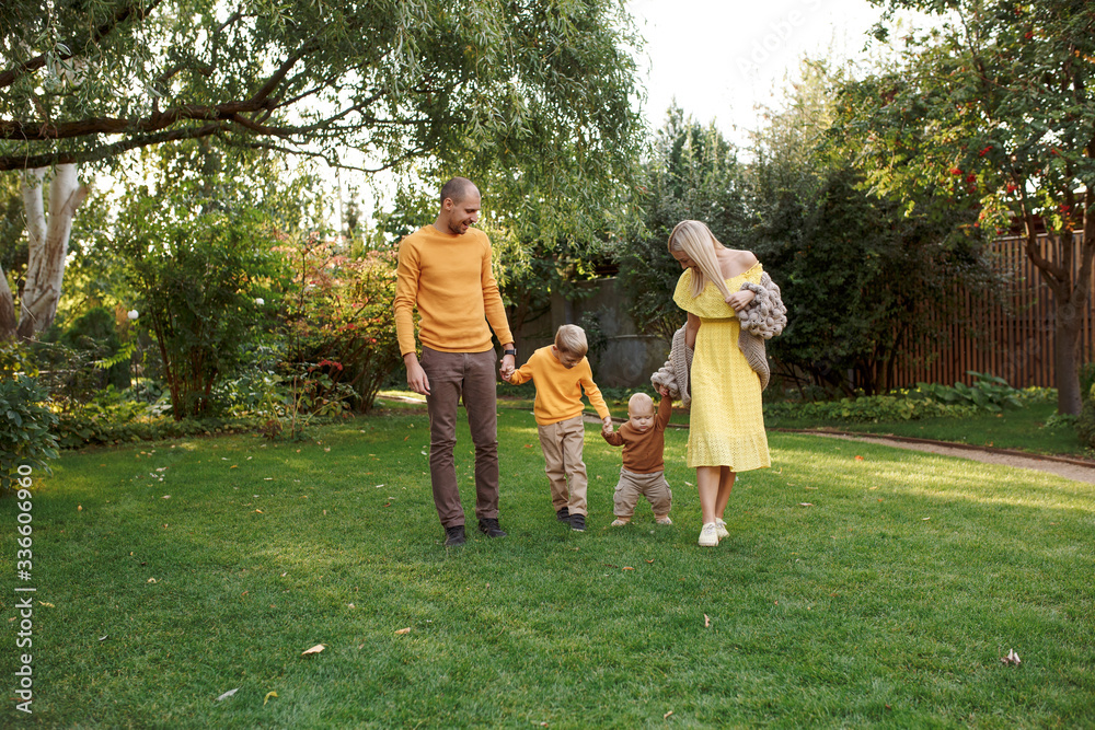 Obraz premium family in nature, summer or autumn, green grass trees in green leaves, a pond in nature, mom blonde in a yellow dress, dad, husband, older son and youngest son, two children, a large and happy family