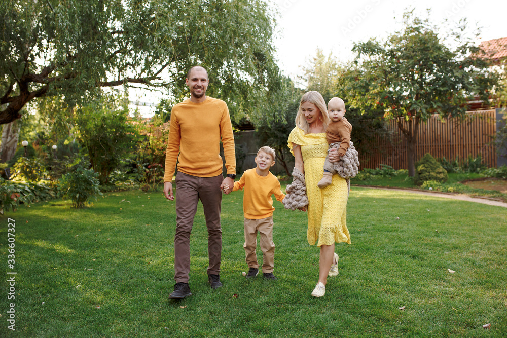 Obraz premium family in nature, summer or autumn, green grass trees in green leaves, a pond in nature, mom blonde in a yellow dress, dad, husband, older son and youngest son, two children, a large and happy family