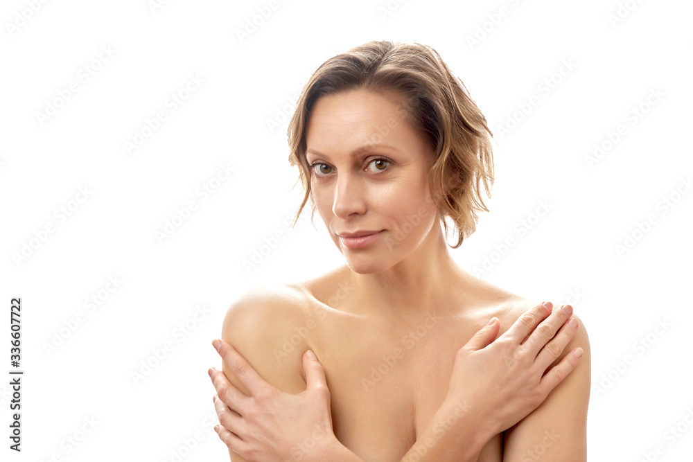 Beautiful young woman with a short haircut hugs herself with her hands. Clean skin. Naked to the shoulders posing. isolated white background. Beautiful young woman with a short haircut hugs herself with her hands. Clean skin. Naked to the shoulders posing. isolated white background.