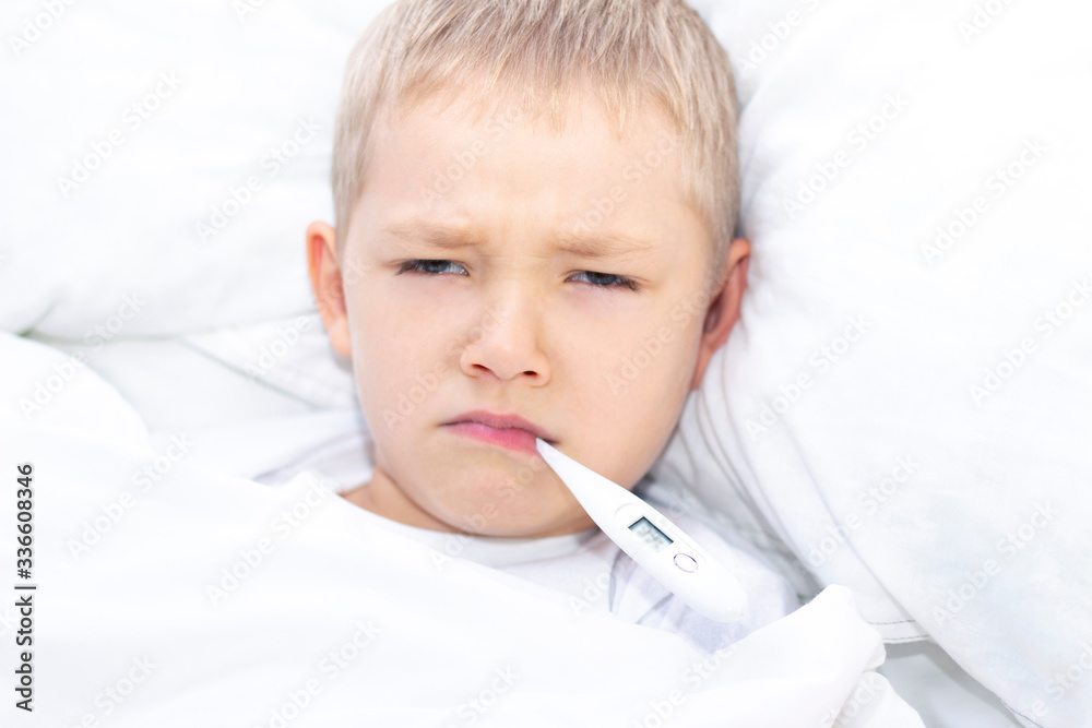 boy lies in bed with a thermometer in his mouth. healthcare concept and sick child, coronavirus, high fever, boy lies in bed with a thermometer in his mouth. healthcare concept and sick child, coronavirus, high fever,