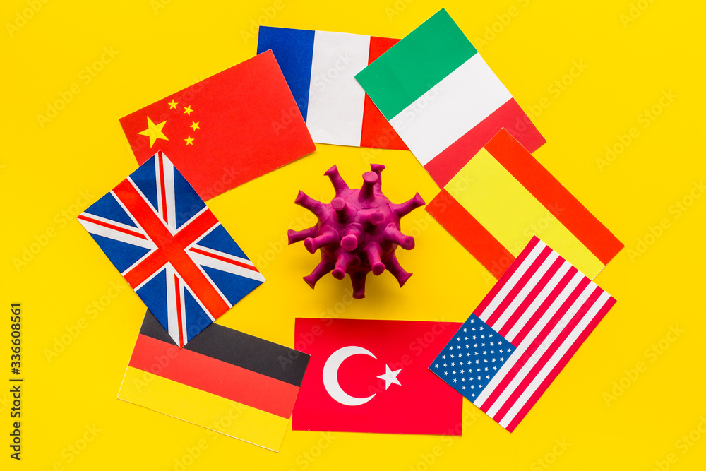Obraz premium Concept of Corona virus Covid-19 epidemic with flags on yellow background top-down
