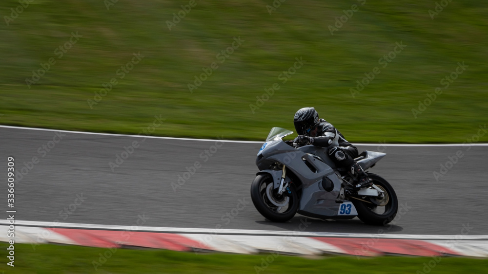 A panning shot of a grey racing bike speeding round corners on a racetrack.