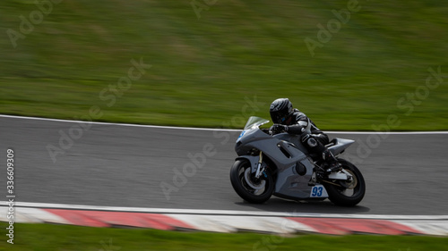 A panning shot of a grey racing bike speeding round corners on a racetrack.