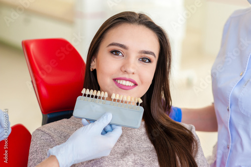Young beautiful women in dentist chair, check and select the color of the teeth.