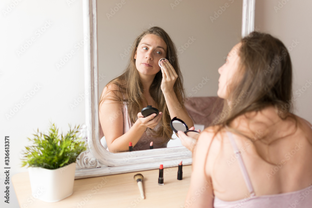 Young woman portrait putting on make up in front of a mirror Young woman portrait putting on make up in front of a mirror