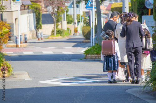 入学式に向かうランドセルをしょった新一年生と保護者の列