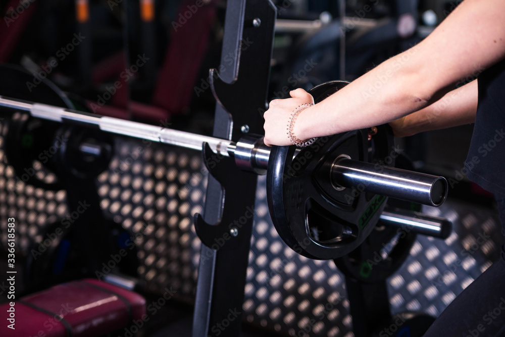 Close-up of a woman holding her hands with a barbell for pulling, squatting, fitness in the gym. Concept sports, toned picture, copy space for text Close-up of a woman holding her hands with a barbell for pulling, squatting, fitness in the gym. Concept sports, toned picture, copy space for text