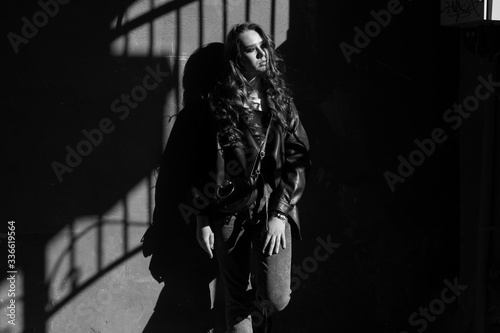 Outdoor portrait of a young elegant woman in hard light with shadows of urban wearing trendy black jacket with incredible makeup. Black and white photography. Close up. Text space.