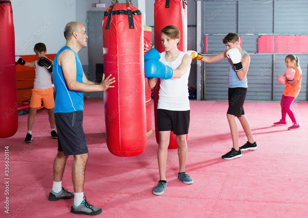Sportsmans at boxing workout on punching bag