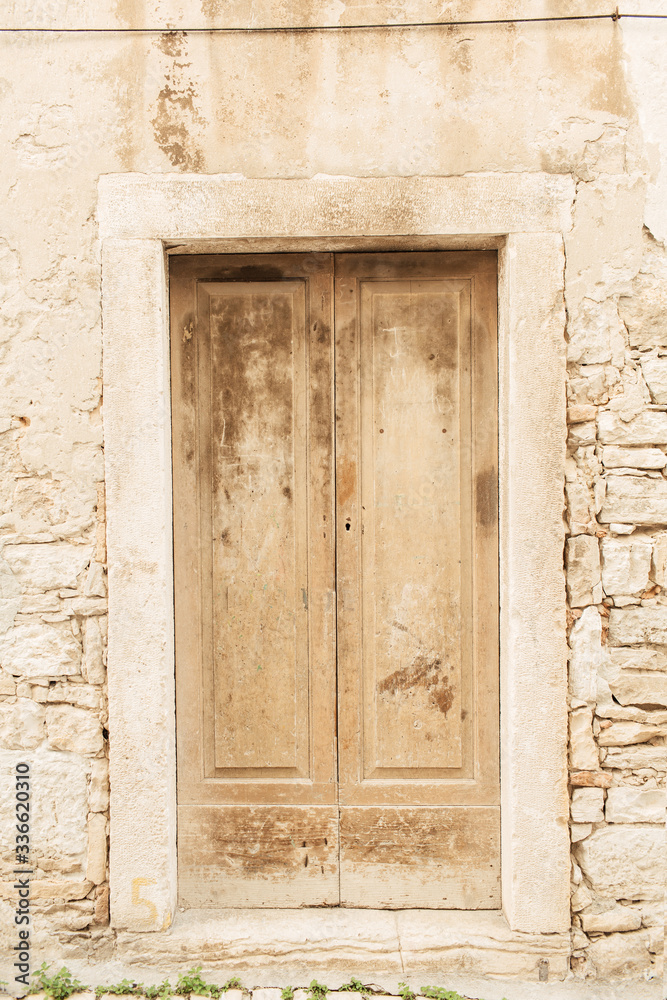 Dubrovnik, Croatia, 2019. Stone building with old vintage beige wooden door. Travel concept.