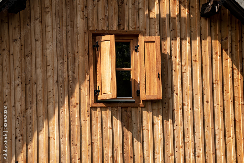 One window with wood shutters on a wooden wall. Close-up of a small cottage in Austrian Alps. Austria, Europe