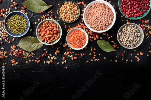 Legumes assortment, shot from above on a black background with copy space. Lentils, soybeans, chickpeas, red kidney beans, a vatiety of pulses