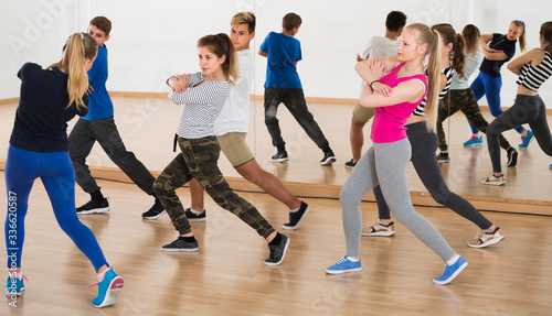 attentive teenage boys and girls learning in dance hall