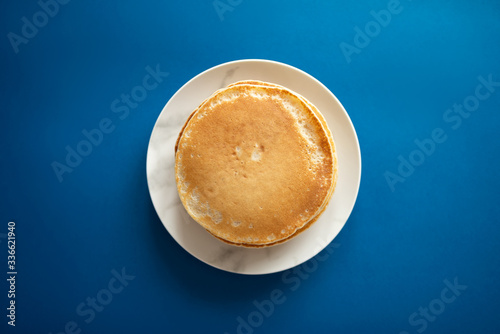 Fresh pancakes on a white dish. Classic blue background. 2020