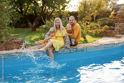 family in nature  summer or autumn  green grass trees in green leaves  a pond in nature  mom blonde in a yellow dress  dad  husband  older son and youngest son  two children  a large and happy family