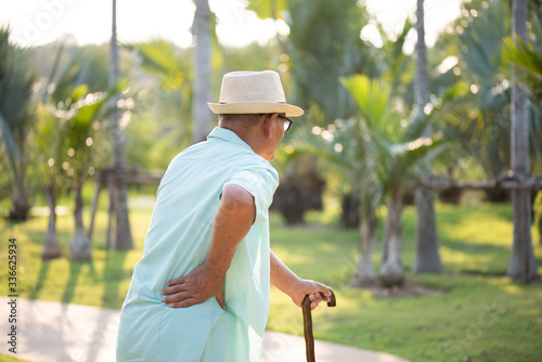 Photography Asian old man walking in park and having a back pain, backache