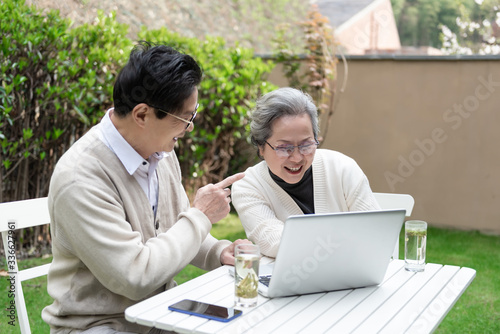 An Asian elderly couple is using a laptop