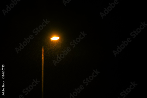 A glowing street lamp at rainy night.